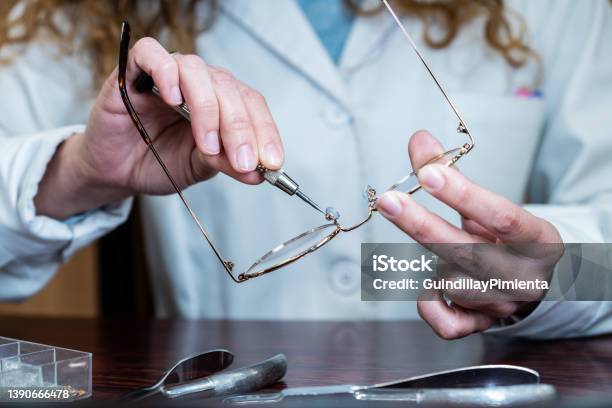 Female Optician Repairing And Fixing Eye Glasses With Screwdriver Hands Holding A Mini Screwdriver Maintenance And Cares Service Frontal View Stock Photo - Download Image Now