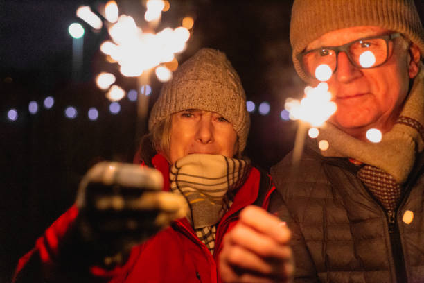 happy senior couple together holding sparklers outdoors - independence spark fire flame imagens e fotografias de stock