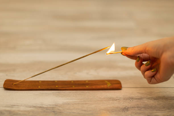la main d’une femme avec une allumette met le feu à un bâton d’encens - baton d'encens aeration photos et images de collection