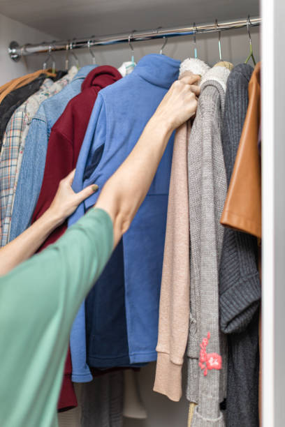 istock woman sorting through things hanging on hangers in the closet 1390668509