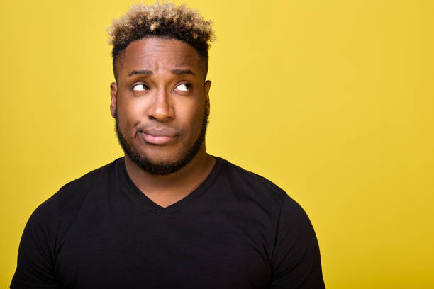 Dark-skinned man with beard with smirk on his face looks to side in disapproval