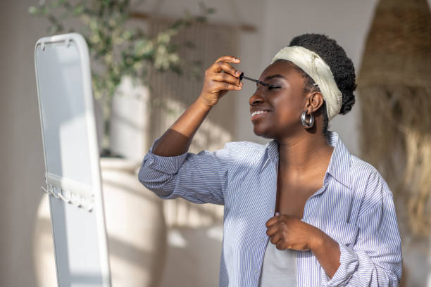 istock Contented african woman holding mascara in hands 1390674380