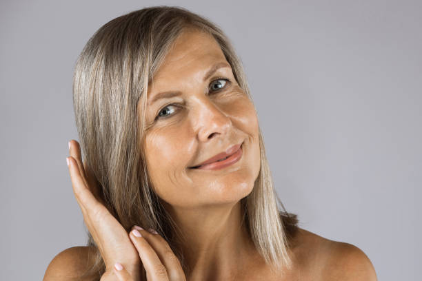 istock Mature woman with bare shoulders touching gently her cheek 1390674411