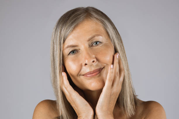 istock Aged woman touching her smooth skin over grey background 1390674459