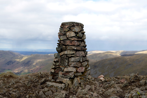 Ordnance Survey stone trig point at mountain summit.