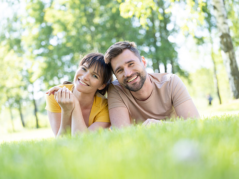 Pretty young lady is lying on the grass at public park.