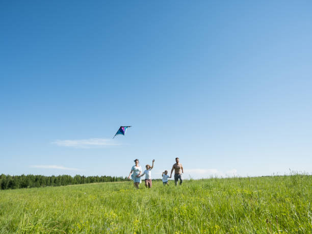 family running through field with fly - child rear view running nature imagens e fotografias de stock