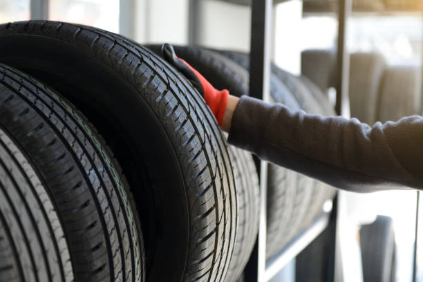 meccanico maschio che tiene il pneumatico durante la riparazione dello sfondo del garage di servizio. - tire foto e immagini stock