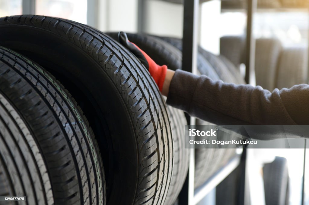 Male mechanic holding tire while repairing service garage background. Tire - Vehicle Part Stock Photo
