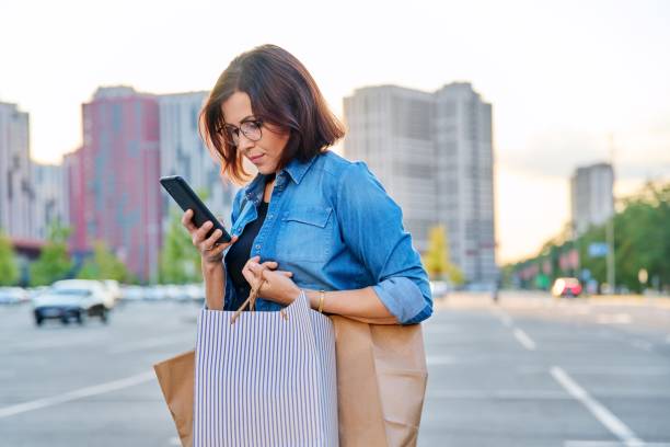 istock Middle aged woman using smartphone in the city 1390677943