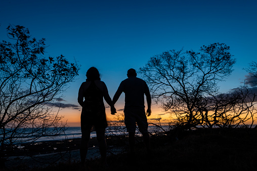 Couple holding hands as they view the sunset at a beach in Costa Rica.