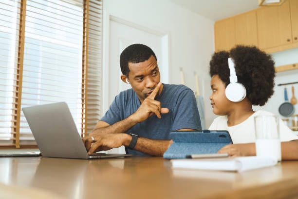 アフリカ系アメリカ人の父親は、自宅で仕事をしている間に息子を黙らせます。 - inconvenience meeting business distracted ストックフォトと画像