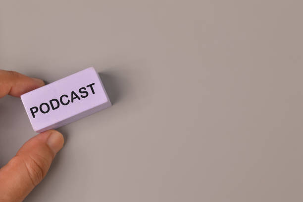istock Hand holding wooden block written with PODCAST. 1390680565