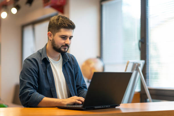 istock Happy young man using his laptop while sitting in the office 1390682373