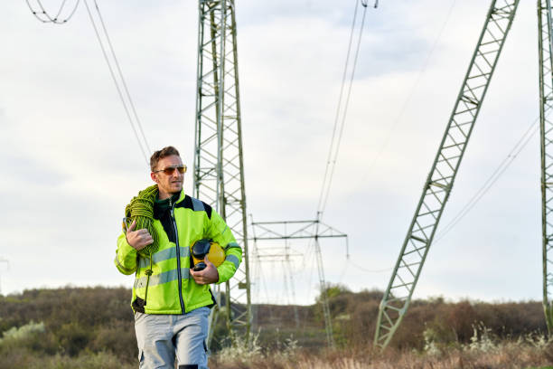 istock Electrical engineer with sunglasses walking away from high-voltage towers after work 1390682557