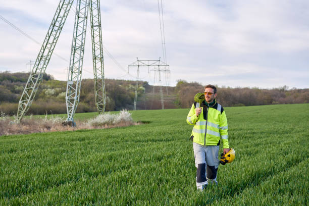 istock Electrical engineer with sunglasses walking away from high-voltage towers after work 1390682559