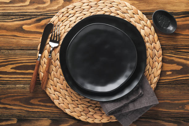 istock Ceramic empty black plate, silverware and linen kitchen towel napkin on old brawn wooden table background. Cooking stone backdrop. Top view with copy space. Flat lay 1390682698
