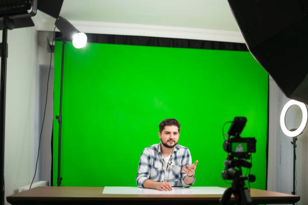istock Young handsome man vlogging in a studio against green background 1390683340