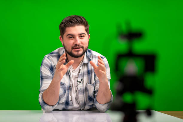 istock Young handsome man vlogging in a studio against green background 1390683491