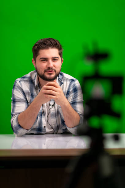 istock Young handsome man vlogging in a studio against green background 1390683521