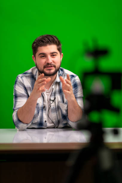 istock Young handsome man vlogging in a studio against green background 1390683556