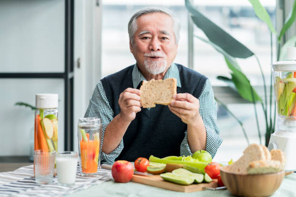 아시아 의 노인 남성 동영상 블로그는 휴대 전화에 요리를 가르칩니다. 남성 노인 동영상 블로그, 오래 된 요리사 는 집에서 히스 샐러드와 주입 된 물을 준비에 대 한 그의 휴대 전화에 비디오 � - heathy food 뉴스 사진 이미지
