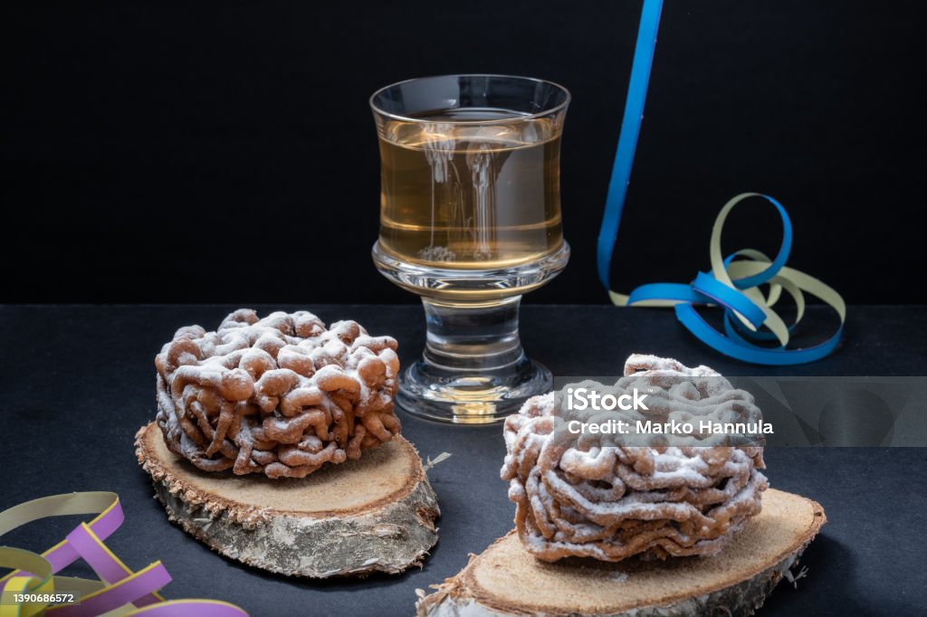 Traditional Finnish cuisine: Funnel cakes with powdered sugar topping are eaten around May 1st with homemade Sima (mead) Helsinki / Finland - APRIL 10, 2022: Traditional Finnish cuisine: Funnel cakes with powdered sugar topping are eaten around May 1st with homemade Sima (mead) Cake Stock Photo