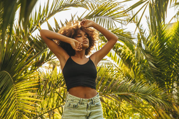 istock Pretty young afro woman among palm trees 1390686622