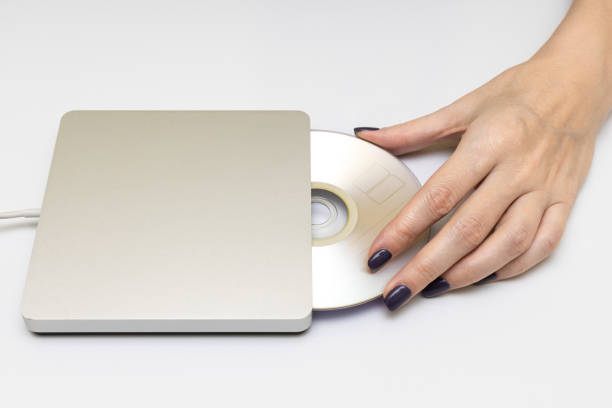 istock Female hand puts a CD into the drive 1390686855