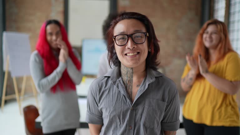 Portrait of a transgender businessman being applauded by the team in the office