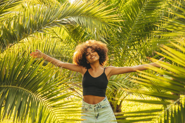 istock Pretty young afro woman among palm trees 1390687657