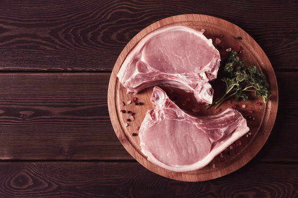 fresh, raw pork meat, sliced, on a cutting board, with spices, horizontal, rustic style, toning - karbonade stockfoto's en -beelden