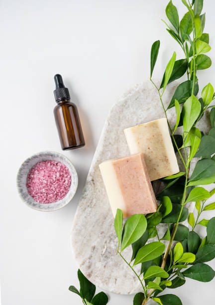 concept flat lay of facial and body care cosmetics with pink sea salt, soap and cream on white  background with brunch. top view and copy space. vertcal orientation - vertcal imagens e fotografias de stock