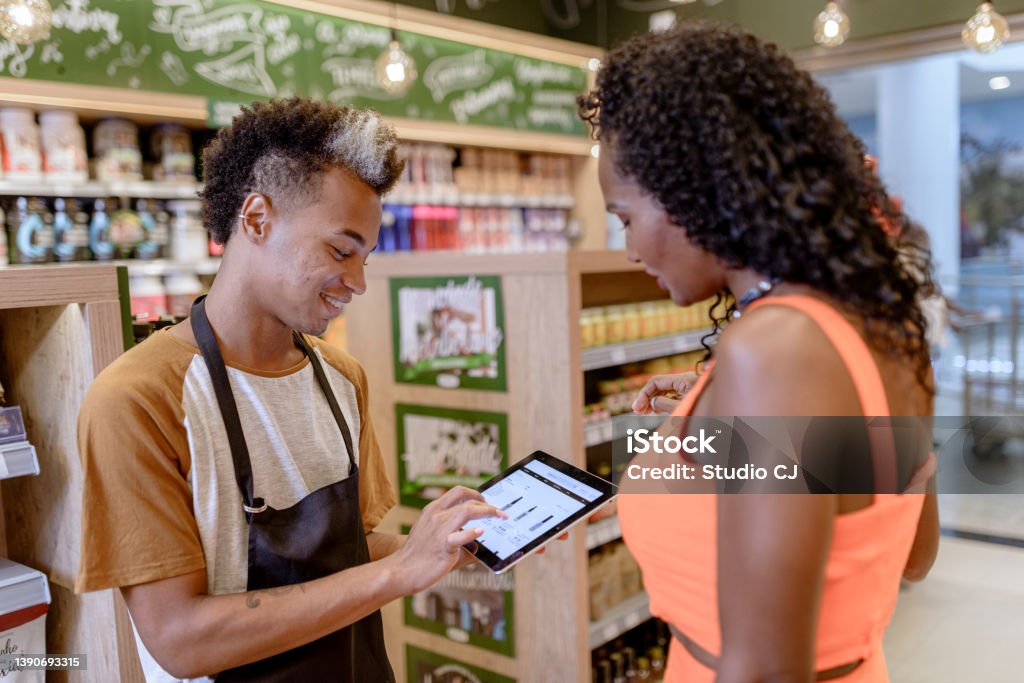 Salesperson presenting products in the store's e-commerce using digital tablet Salesperson presenting products in the store's e-commerce using digital tablet. Sale Stock Photo