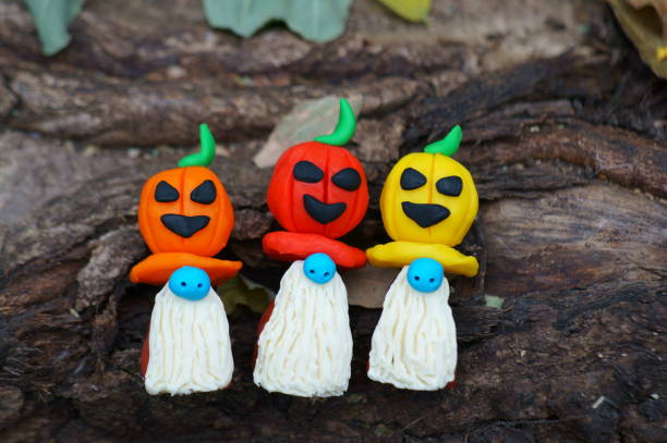 istock Figures of three dwarfs decorated with a pumpkin on a background of tree bark. 1390696803