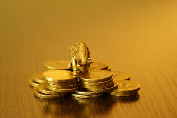 istock A metal bull with coins on a gold background. 1390697040