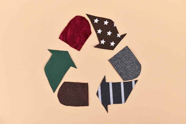 Recycling arrow symbol made from old textile pieces on beige background