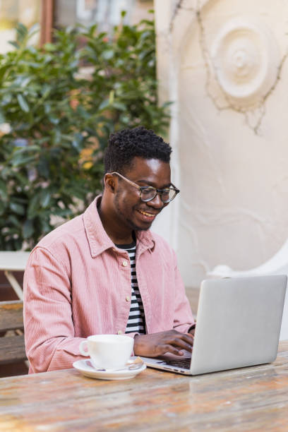 istock Smiling African-American man using laptop outside 1390697297