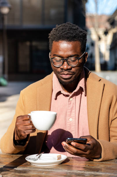 istock Portrait of an African-American man using smartphone outside while drinking coffee 1390698203