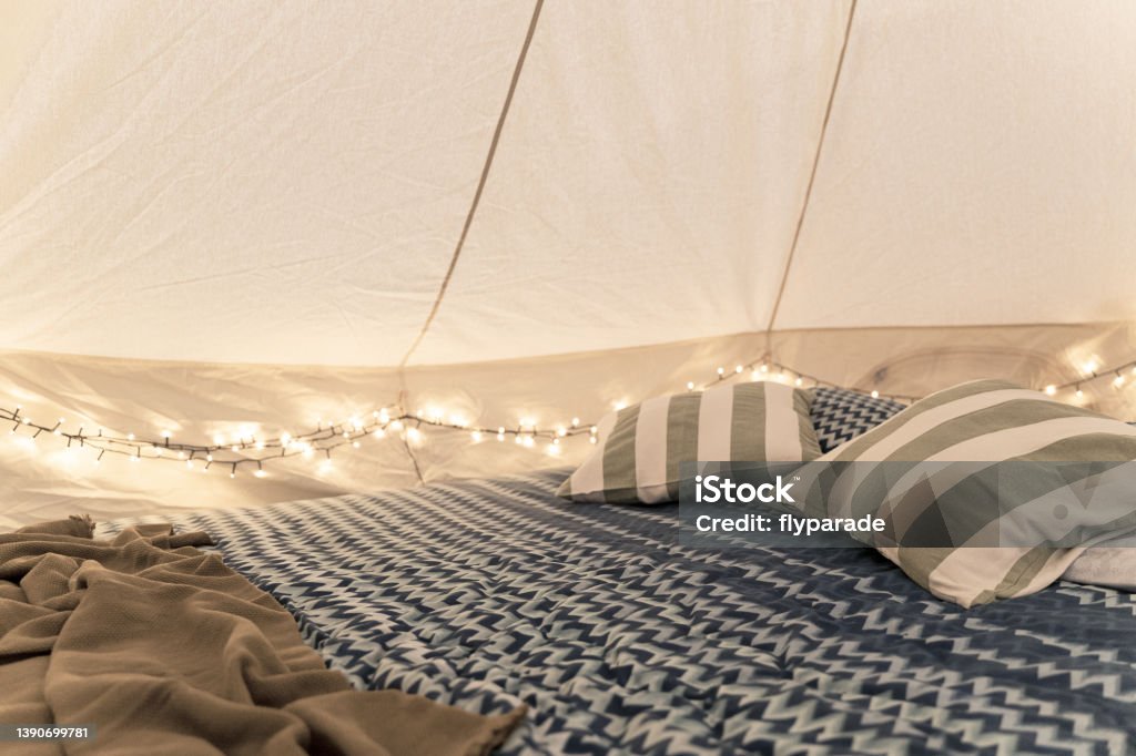ベッド枕と親密なライトを備えたグランピングテントのインテリアディテール - グランピングのロイヤリティフリーストックフォト