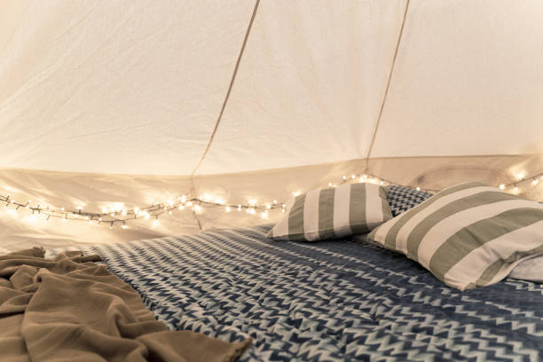 glamping tent interior detail with bed pillows and intimate lights stock photo