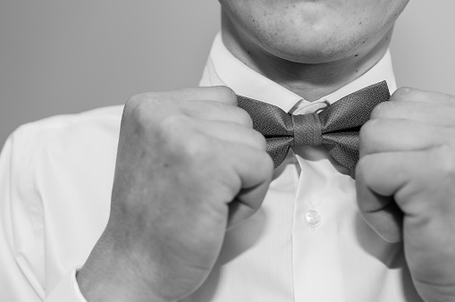 Golden bow tie in the hands of the groom. Bow tie in the hands of a man