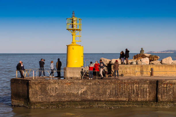 Senigallia, Italy - April 10, 2022: Group of people in the Senigallia pier (Marche, Italy). Group of people observing the Yellow Lantern of the city of Senigallia.