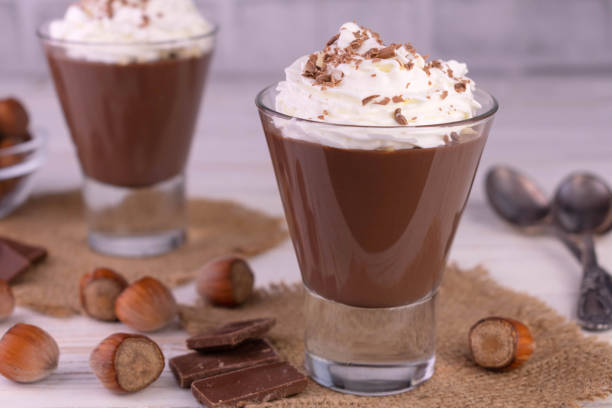 istock Chocolate mousse with hazelnuts and cream on a white wooden background. 1390703026