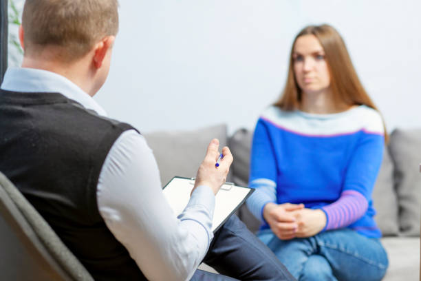 istock Professional help. The psychologist professional is talking to a client. The psychologist with clipboard taking notes and listening to female patient in psychotherapy session 1390705838