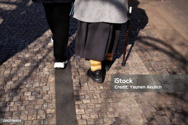 Elderly Woman With A Cane Walking Down The Street Rearview Old Couple Holding Hands Together The Concept Of Old Age Diseases Of The Joints And Spine Stock Photo - Download Image Now