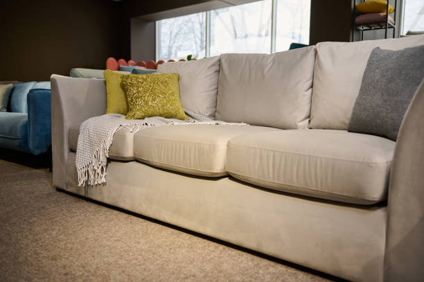 istock Comfortable upholstered velour beige couch with colored gray and green olive cushions displayed for sale in the furniture store showroom. Exhibition of upholstered furniture. 1390707739