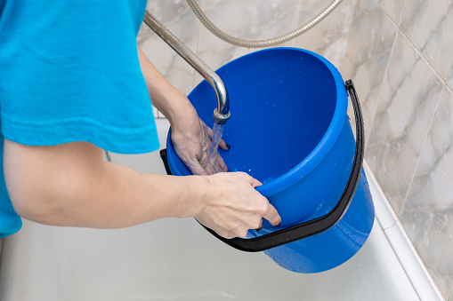 woman washes a bucket from the inside with her hand