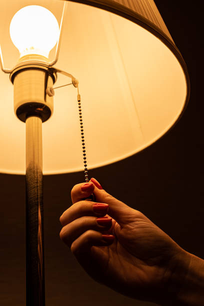 istock woman pulling the switch chain of a floor glowing lamp 1390708035