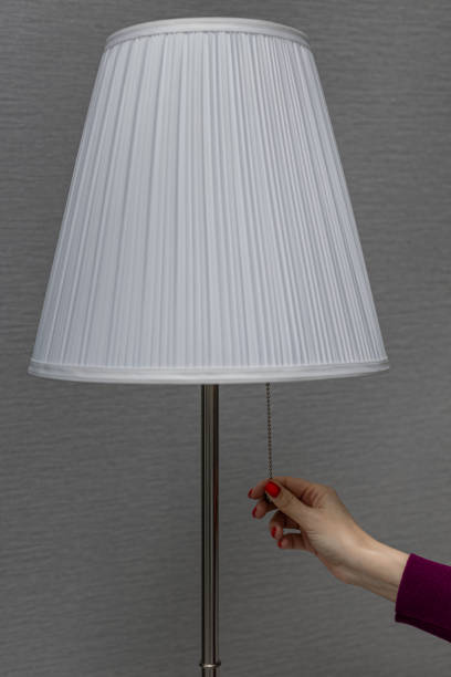 istock a woman turns on a floor lamp by pulling the switch chain 1390708062